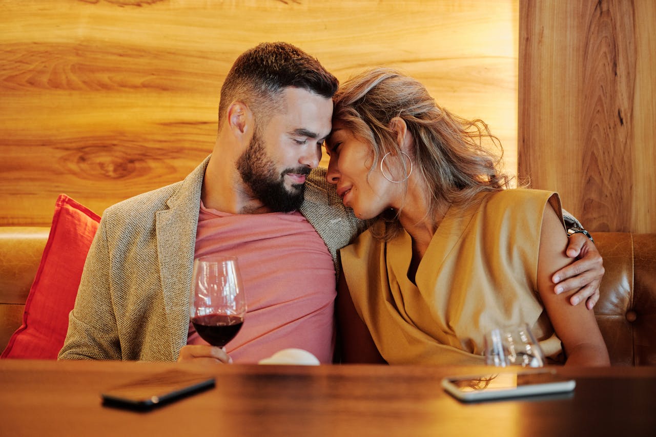 services-02 A couple shares an intimate moment with wine glasses at a cozy restaurant setting.